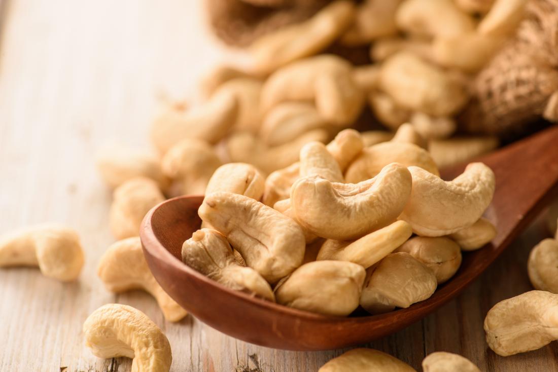 Cashew nuts on wooden spoon.